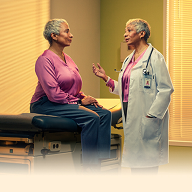 Female doctor talking to female patient sitting on an exam table