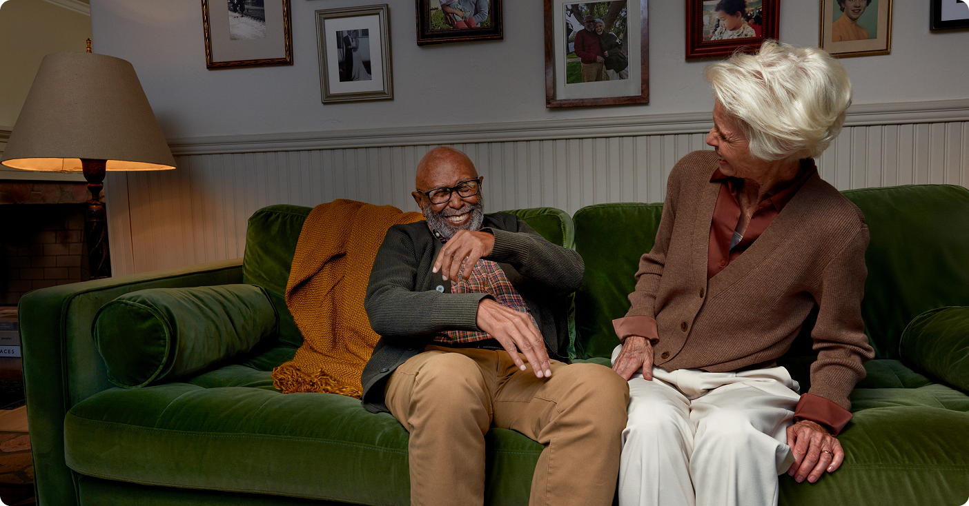 Elderly couple sitting on a couch laughing