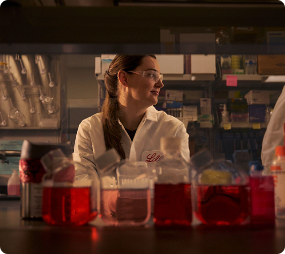 Woman in Lilly lab coat with lab testing equipment in the foreground