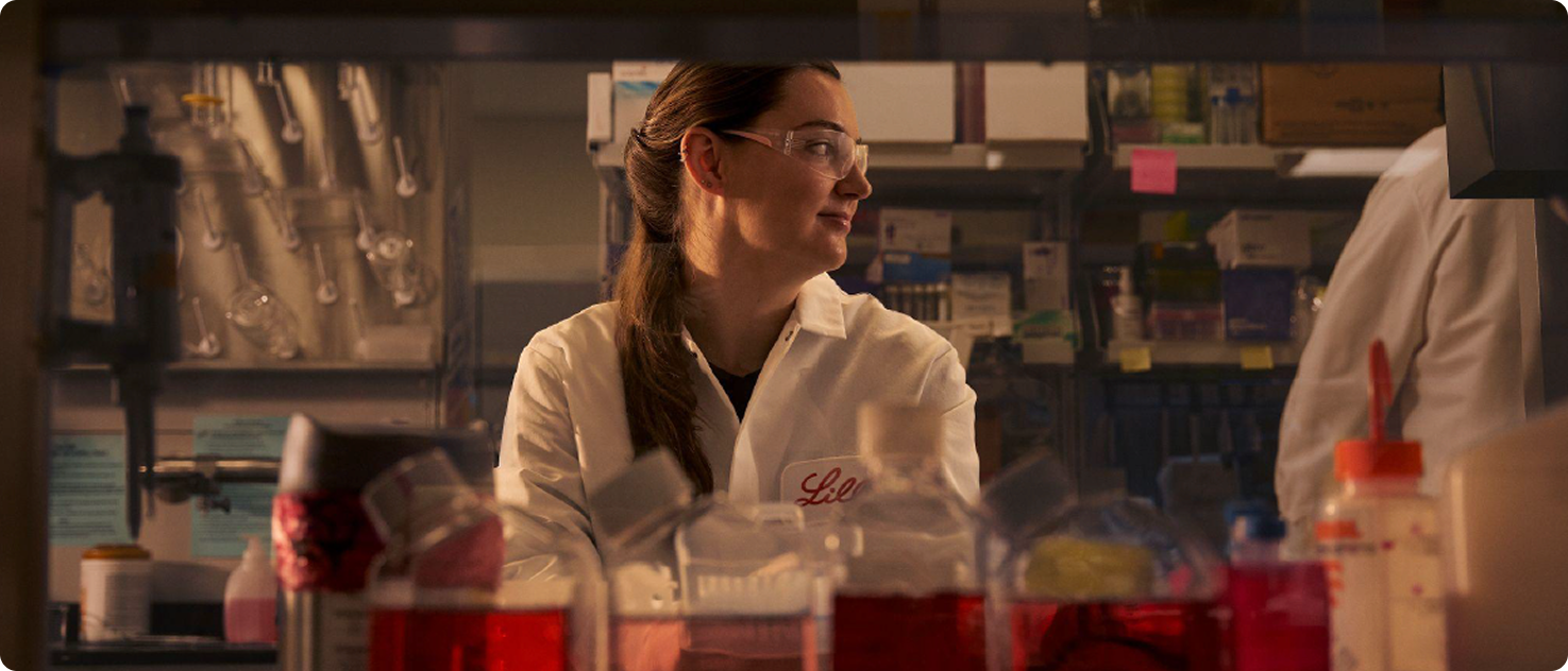 Woman in Lilly lab coat with lab testing equipment in the foreground