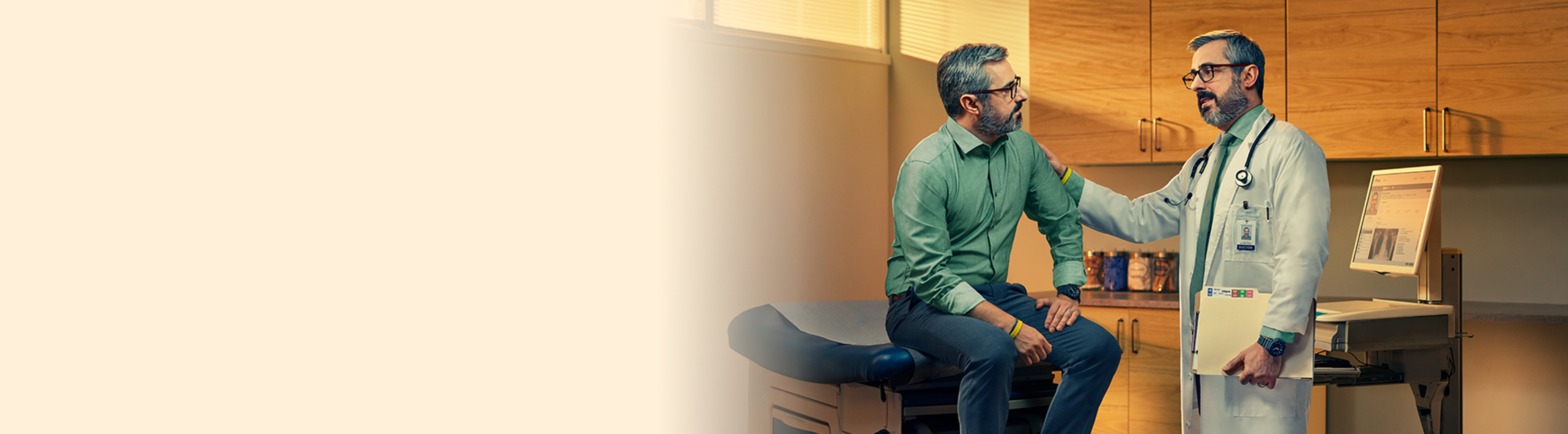 Doctor with hand on patient shoulder sitting on exam table